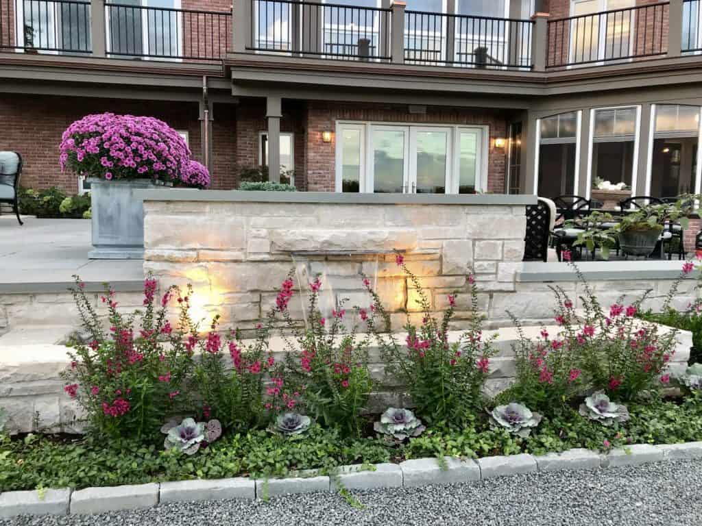 Custom waterfall feature integrated into bluestone patio seat wall in Barrington, IL | Milieu Landscaping