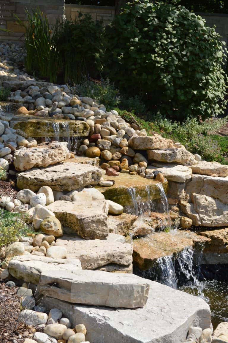 Backyard waterfall with limestone tiers | Milieu Landscaping