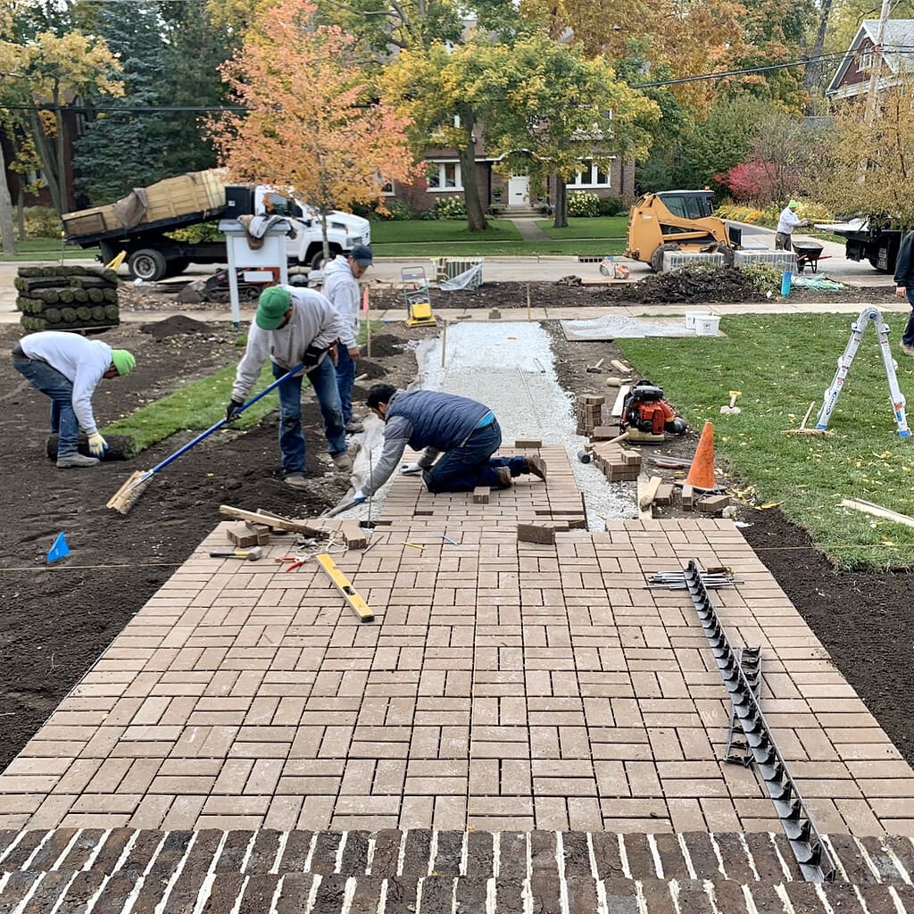 Hardscaping crew laying brick paver walkway to the front entry | Milieu Landscaping