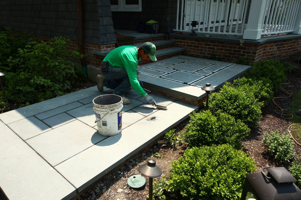 Landscape mason laying bluestone tiles for front entry walkway in Winnetka, IL | Milieu Landscaping