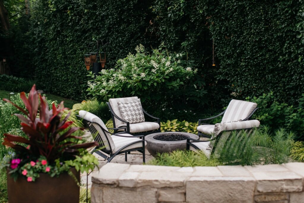 Overlooking the custom fire pit patio with seating from the upper dining terrace seat wall in Northbrook, IL | Milieu Landscaping