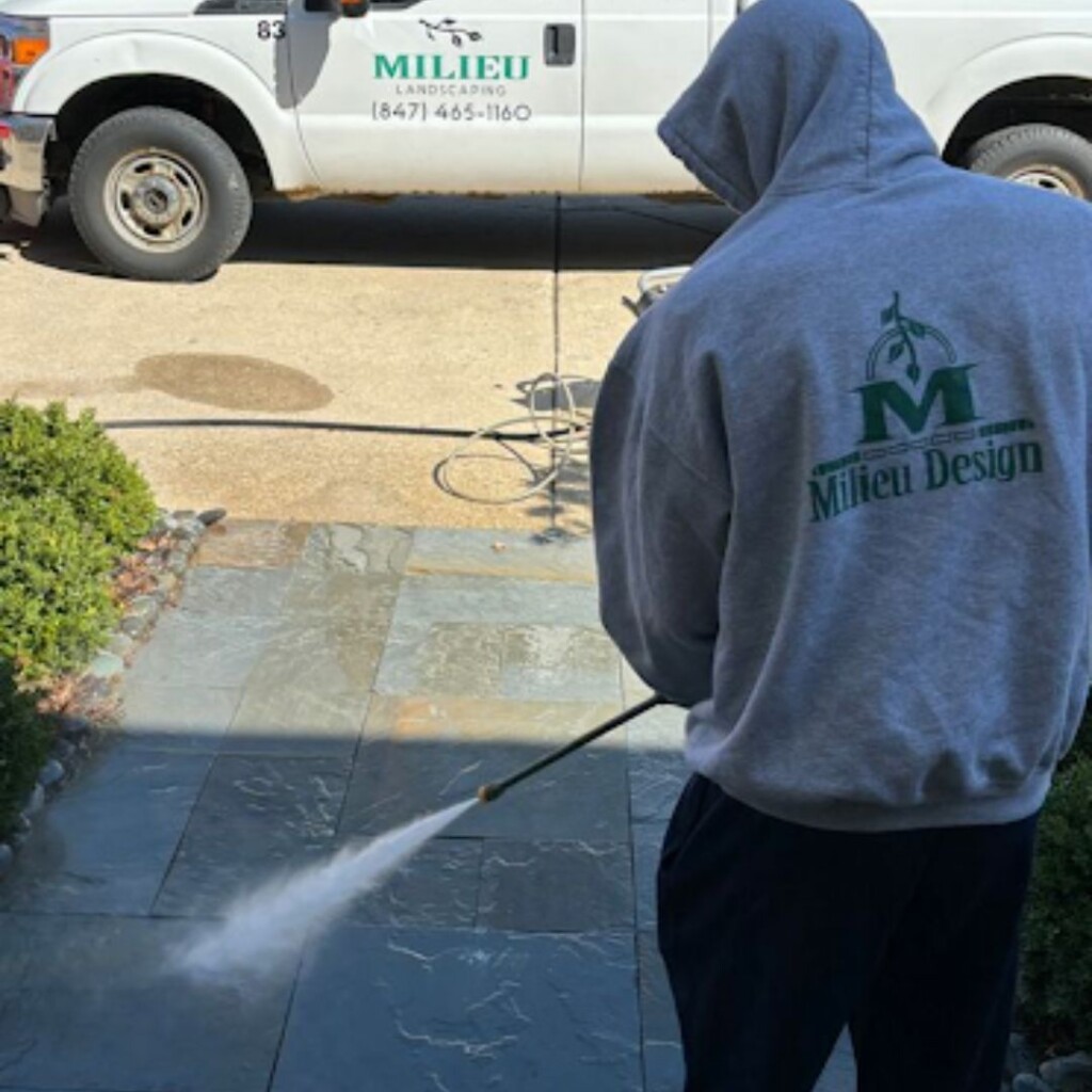 worker cleaning driveway with pressurized water